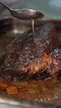 Close up of gently basting juicy freshly roasted meat with its own savory cooking juices
