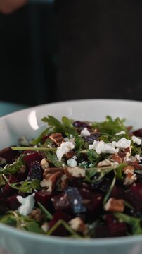 Close up of fresh arugula falling onto a beetroot and nut salad
