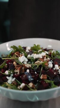 Close up of fresh arugula falling onto a beetroot and nut salad
