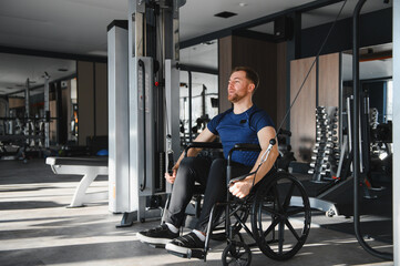 Obraz premium Man with disability, athlete doing rehabilitation exercises with cable machine in gym