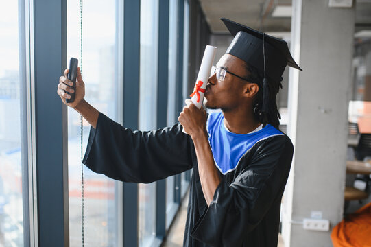 Graduate student kissing diploma and taking selfie with smartphone