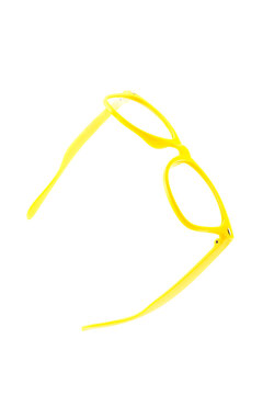 glasses plastic yellow without lenses lie half turned on an isolated white background