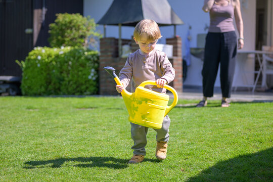 Toddler Carrying Watering Can Outdoors