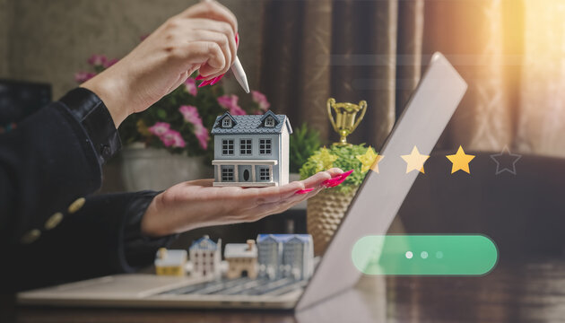 Online property booking and customer feedback concept. Hands evaluating a model home with virtual five-star rating and green action button.