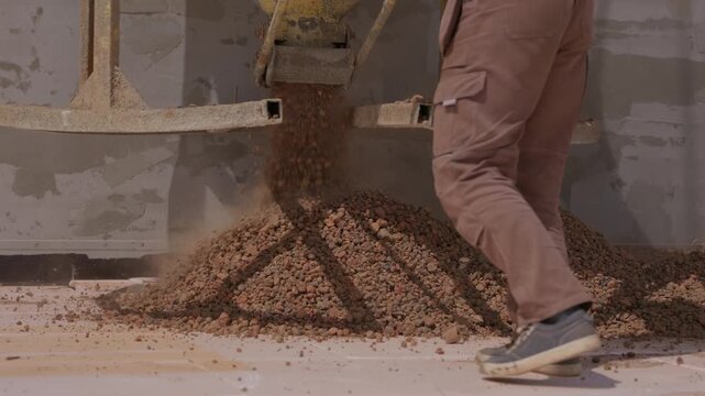 Pouring expanded clay aggregate insulation onto flat roof during construction
