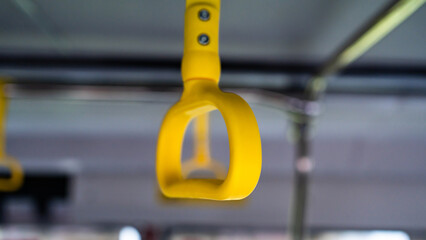 Yellow passenger hand strap hanging inside a public transit bus with a beautifully blurred background © Andik