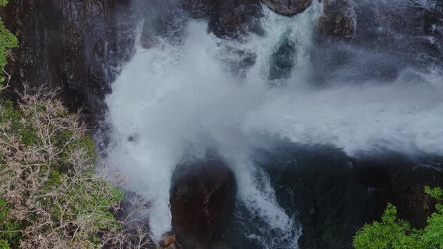 Water from powerful waterfall splashes on natural river rocks in Yakushima, Japan