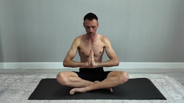 A bare-chested man sitting in the lotus position and practicing yoga and meditation
