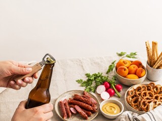 Fototapeta premium Cerveza y aperitivos en una mesa con salchichas, pretzels y fruta fresca