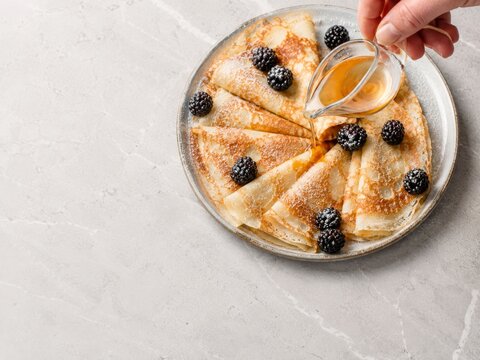Preparaci&oacute;n de crepes con moras y jarabe en un plato