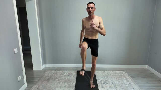 A bare-chested athlete in shorts performs leg muscle development exercises with elastic bands