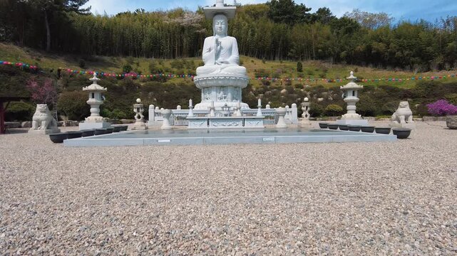 Slow zoom towards a large stone Buddha statue in a serene Buddhist temple in South Korea