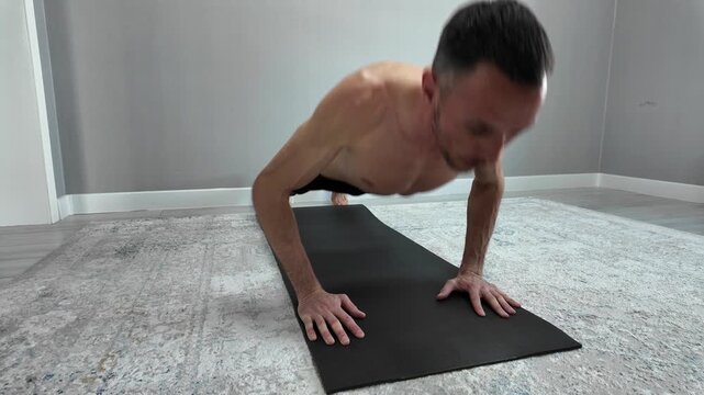 A strong, muscular man performs intense push-ups on a yoga mat