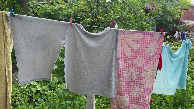 Clean laundry items drying on a clothesline in a sunny garden Simple daily household chore in rustic setting.