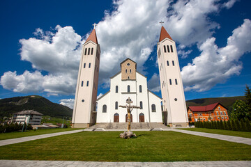 Naklejka premium Church of the Holy Family with Two Towers and Crucifix Sculpture under Dramatic Sky in Kupres Bosnia and Herzegovina