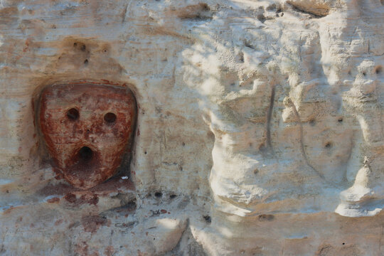 Engraving depicting a faces. Rock drawings and scratch-carvings, pictographs and abstract signs made with red ochre on the limestone cliffs along the "Cammino del Salento" hiking trail. Puglia Region,