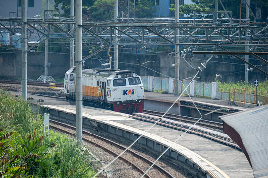 Jakarta, Indonesia - July 02, 2026: Vintage-liveried KAI locomotive arriving on the curved tracks at Kampung Bandan Station beneath overhead catenary lines.