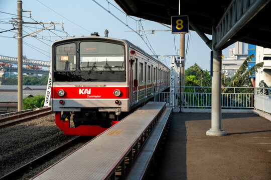 Jakarta, Indonesia - July 02, 2026: A KAI Commuter JR East 205 series train arrives at Platform 8 of Kampung Bandan Station beneath overhead catenary wires in the late afternoon.