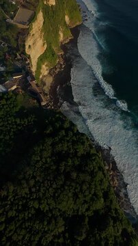 Vertical video. Aggressive FPV Drone Dive Along Karang Boma Cliff Above Ocean Breakers, Dynamic First Person Perspective Over Rugged Coastline, Courage And Adventure