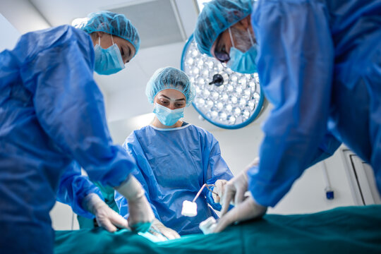 Focused surgical team during medical operation in hospital. Doctors and nurse in protective gear working together in operating theater. Healthcare, surgery and professional medical procedure concept.