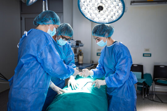 Surgical team performing operation in modern operating room. Surgeons and nurse in scrubs and masks focusing on procedure. Healthcare, medicine, hospital surgery, professional medical teamwork.