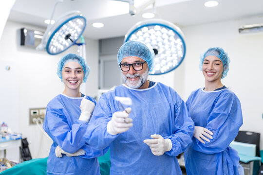 Portrait of professional surgical team smiling in operating room. Doctors and nurses wearing blue scrubs, masks and caps after successful surgery. Healthcare, medicine, hospital team success.
