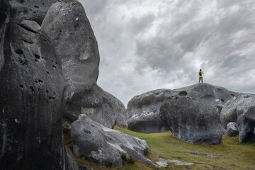 A solitary figure stands dwarfed among towering limestone boulders at Castle Hill (Kura Tawhiti) in the Canterbury high country, South Island, New Zealand © ting_149