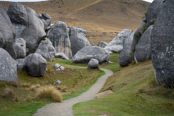 A gravel walking path winds gently through towering limestone boulders at Castle Hill (Kura Tawhiti) in the Canterbury high country, South Island, New Zealand. © ting_149