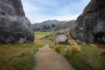 A wooden staircase descends through massive limestone boulders at Castle Hill (Kura Tawhiti), framed by two towering weathered rock formations on either side Canterbury New Zealand © ting_149