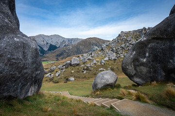 A wooden staircase descends through massive limestone boulders at Castle Hill (Kura Tawhiti), framed by two towering weathered rock formations on either side Canterbury New Zealand © ting_149