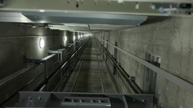 View from elevator car inside shaft with guide rails and maintenance lighting