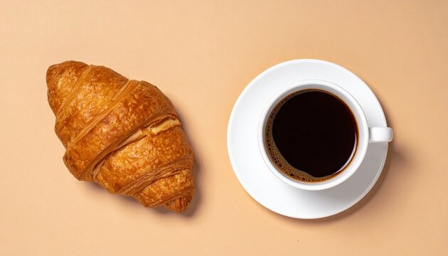 A fresh croissant and a cup of black coffee on a light brown background, cozy breakfast, coffee and bakery.