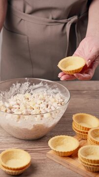 Filling tartlets with chicken salad medium shot. Woman stuffing appetizer with spoon. Cooking festive recipe at home, slow motion 4K video 25fps.