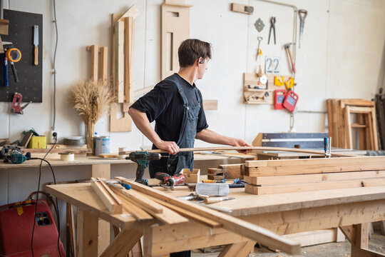 Busy workday at restoration workshop, craftsman working with wooden materials for frame repair, woodworker in carpentry preparing planks for replacement, process of reconstruction and manufacturing.
