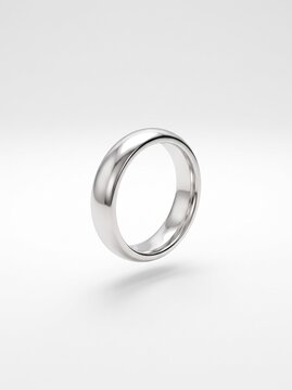 A silver ring is displayed on a plain surface in a studio setting.