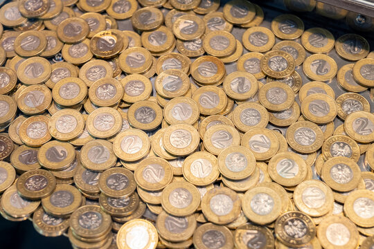 Large pile of Polish 2 zloty coins inside a traditional coin pusher arcade machine, close-up full frame of gold and silver currency, gambling, jackpot, luck and cash background, no people visible