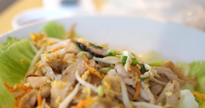 Close up of hand squeezing fresh lime juice onto Thai roasted chicken noodles