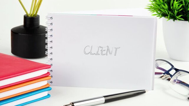 A notebook shows letters Client changing from unclear to clear in an office space. Colorful notebooks are arranged with a plant and stationery nearby