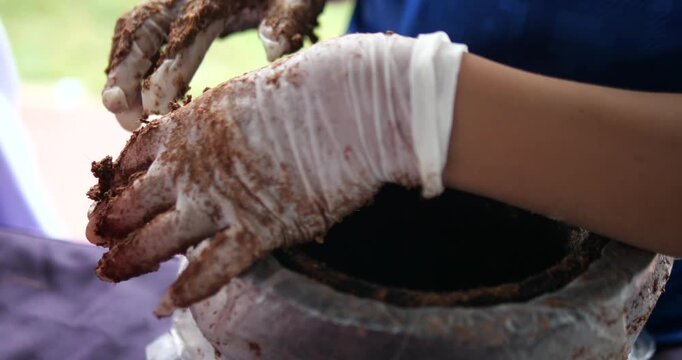 Close up of hands in gloves packing coconut coir soil into eco friendly pot