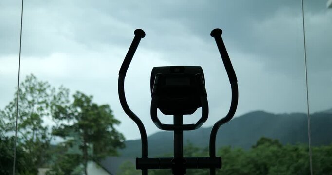Silhouette of elliptical cross trainer machine with mountain view background