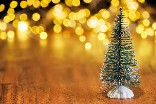Christmas or New Year greeting card template with snow covered miniature Christmas trees and Christmas lights in the background. Xmas holidays atmosphere. Image with copy space and selective focus.