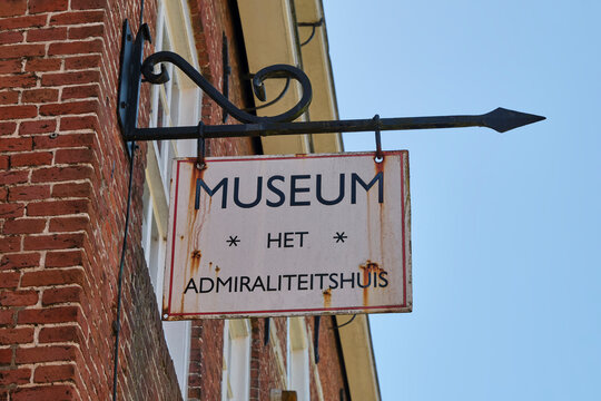 A weathered sign indicating the location of the Het Admiraliteitshuis museum in Dokkum Friesland The Netherland is mounted on a traditional brick facade against a clear blue sky.
