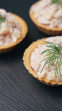 Ready chicken salad tartlets rotating on black slate close up. Festive appetizer turning on turntable at home. Cooking recipe, slow motion 4K 25fps.