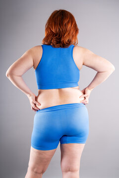 Rear view of woman pinching back fat and love handles. Concept of weight loss, liposuction and body contouring