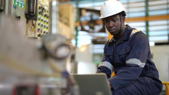 Maintenance technician reviewing production data, industrial control panel, laptop operation, machine diagnostics, factory maintenance, manufacturing process, engineering workflow.