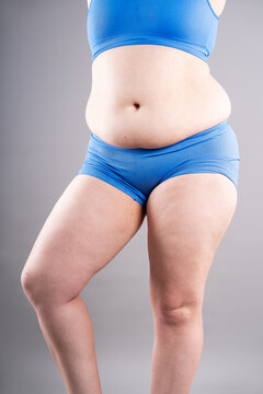 Overweight woman in blue sportswear showing belly fat and cellulite, weight loss and abdominal distention concept
