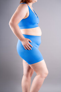 Overweight woman in blue sportswear showing belly fat and cellulite, weight loss and abdominal distention concept