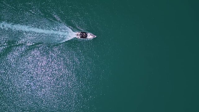 Aerial top down view of a motorboat speeding through turquoise ocean water