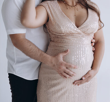lose-up of pregnant woman in sequin dress with husband holding her belly