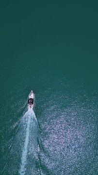 Aerial top down view of a motorboat speeding through turquoise ocean water